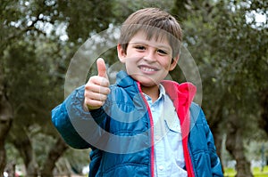 Portrait of a cute blond-haired boy, thumbs up and smile