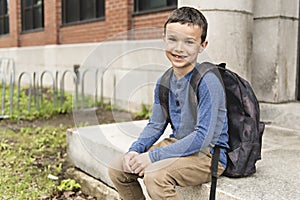 Portrait of cute boy with backpack outside of school