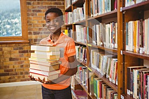 Portrait of cute boy carrying books in library