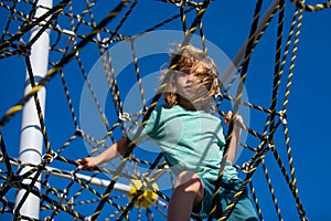 Portrait of cute boy child doing rock climbing in the playbackground. Kids rope Park.