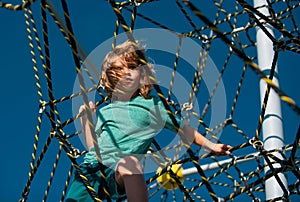 Portrait of cute boy child doing rock climbing in the playbackground. Kids rope Park.