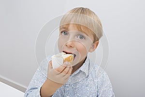 Portrait of cute boy eating cake slice in house