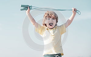 Portrait of cute boy exercising with jumping rope on blue sky background. Kid skipping rope during sunny morning.