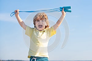 Portrait of cute boy exercising with jumping rope on blue sky background. Kid skipping rope during sunny morning.