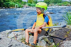 Portrait of cute boy kayaking on the river on a sunny day during summer vacation