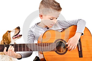 Portrait of a cute boy playing acoustic guitar with his dog