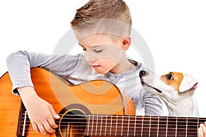 Portrait of a cute boy playing acoustic guitar with his dog Jack Russell Terrier