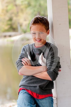 Portrait of cute boy sitting in gazebo with hands crossed.