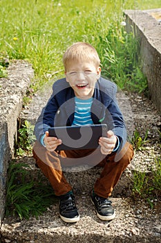 Portrait Cute boy sitting in park and using tablet pc