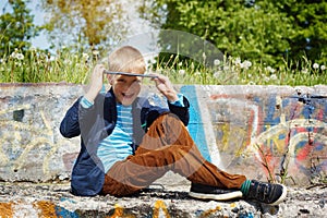 Portrait Cute boy sitting in park and using tablet pc. Educating