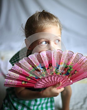 Portrait - cute on bright background little girl with a fan