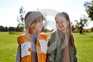 Portrait of cute brother and sister smiling and having fun together while spending time with family in the park