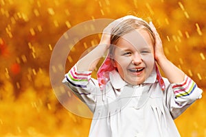 Portrait of a cute charming laughing little girl standing in autumn park in the rain.