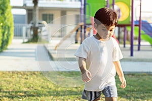 Portrait of cute cheerful baby Asian boy working or running on green grass in at playground