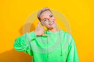 Portrait of cute cheerful person beaming smile arm fingers demonstrate call me gesture isolated on yellow color