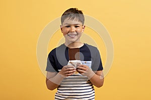 Portrait of cute cheerful preteen kid holding chocolate bar