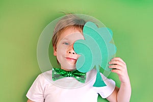 Portrait Cute Child boy holding paper clover shamrock on green background. Irish St. Patrick's Day