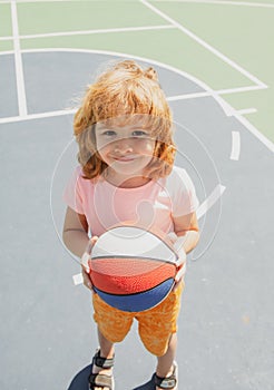Portrait of a cute child boy play basketball. Caucasian kids face.