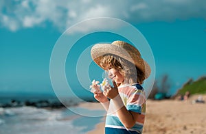 Portrait of a cute child boy in straw hat. Close up caucasian kids face. Closeup head of funny kid on summer beach.