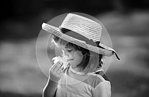 Portrait of a cute child boy in straw hat smelling plumeria flower. Close up caucasian kids face. Closeup head of funny