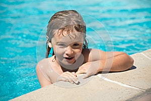 Portrait of cute child boy swim in swimming pool, summer water background with copy space. Funny kids face.