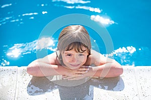 Portrait of a cute child boy in swimming pool. Close up caucasian kids face. Kids summer activities.