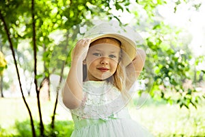 Portrait of cute child girl model in hat smiling in park or outdoor. Happy childhood, summer holidays and vacations