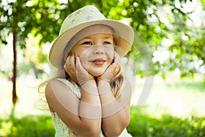 Portrait of cute child girl model in hat smiling in park or outdoor. Happy childhood, summer holidays and vacations