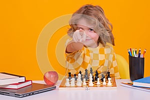 Portrait of cute child play chess on studio isolated background. Kid playing chess. Clever child thinking about chess