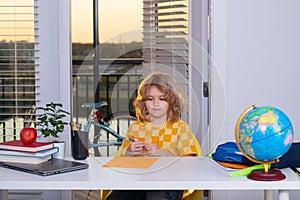 Portrait of cute child school boy writing school homework at table in room. School and education kids concept. Clever