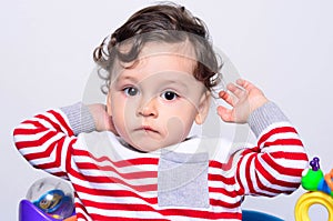 Portrait of a cute curly hair baby boy lifting his hands up.