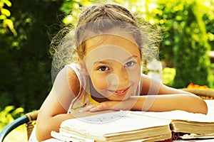 portrait of cute curly school girl reading an old book outside