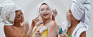 Portrait of cute diverse young women wearing colorful underwear and head towel having fun, trying new beauty products