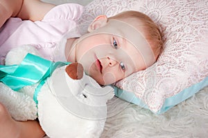 Portrait of cute european little blonde princess girl with bear in beautiful dress lying on the floor in decorated studio in