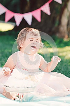 Portrait of cute funny upset sad crying Caucasian baby girl in pink tutu dress celebrating her first birthday
