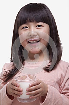 Portrait of cute girl with bangs drinking a glass of milk with a milk moustache photo