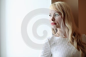 Portrait of a cute girl with blond hair by the window