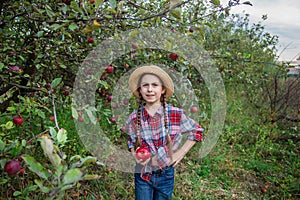 Portrait of a cute girl in a farm garden with a red apple