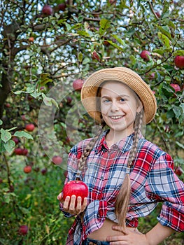 Portrait of a cute girl in a farm garden with a red apple