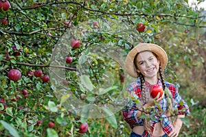 Portrait of a cute girl in a farm garden with a red apple