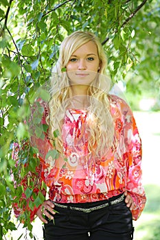 Cute girl in the foliage of a birch