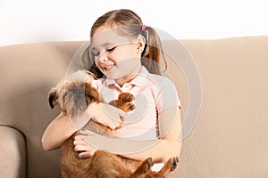 Portrait of cute girl with funny Brussels Griffon dog at home