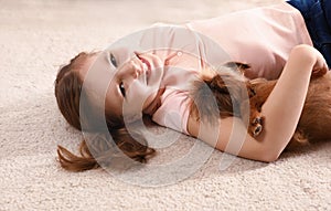 Portrait of cute girl with funny Brussels Griffon dog lying on carpet