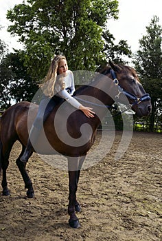 Portrait of cute girl  in helmet  horseback riding on brown horse