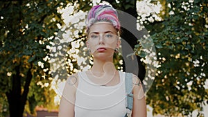 Portrait of cute girl hipster with dyed hair, piercing and tattoo in city park