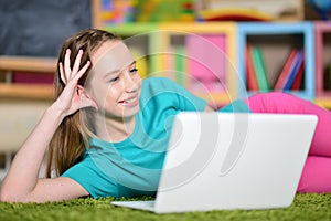 Portrait of cute girl with laptop computer on floor