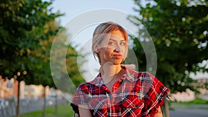Portrait cute girl with long white hair in red checkered shirt is doubts and stares at camera