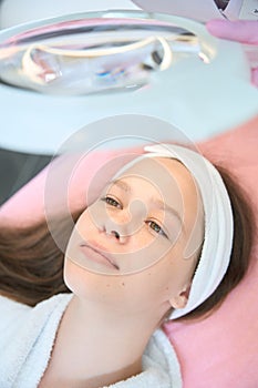 Portrait of cute girl lying under magnifying glass lamp