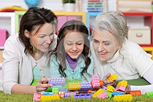 Portrait of cute girl playing with mom and grandma in cubes