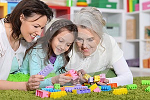 Portrait of cute girl playing with mom and grandma in cubes